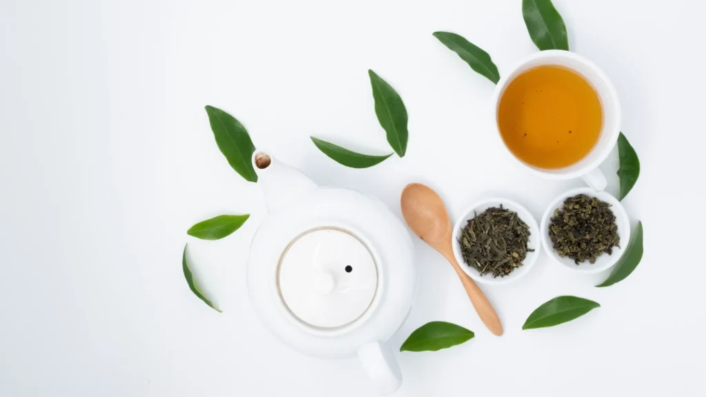 Light green tea in a cup with fresh tea leaves