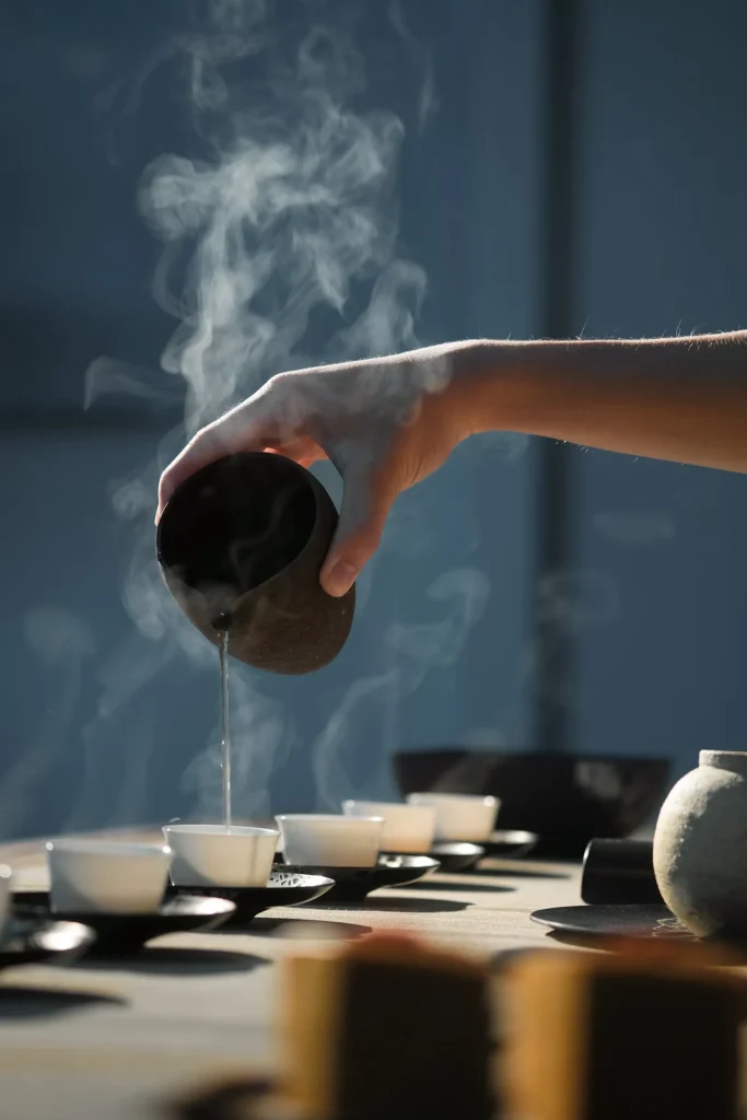 Person pouring Chinese tea into small teacups