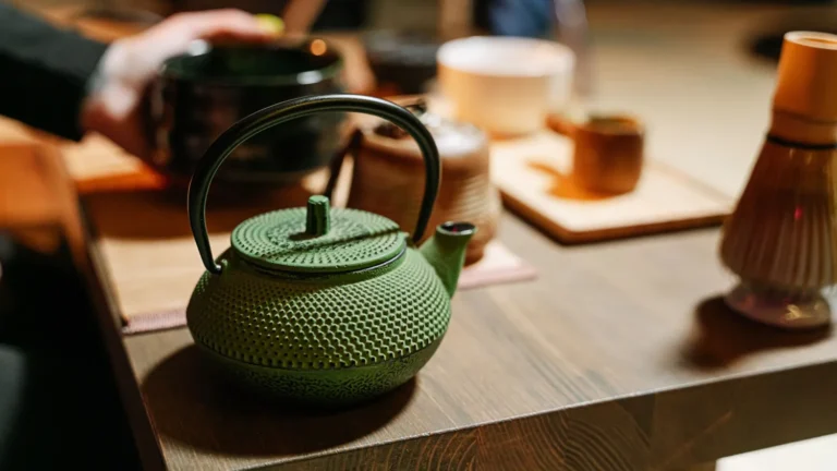 Green cast iron teapot on a wooden table in a minimalist home tea corner
