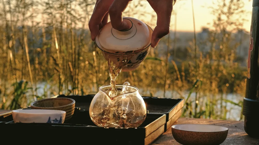 pouring hot tea into a glass teapot