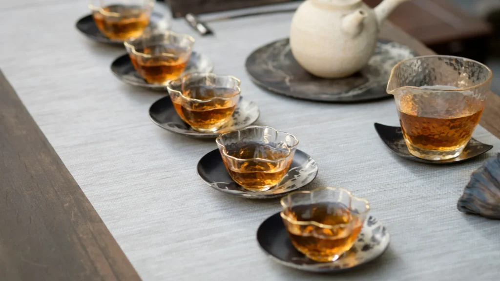 A traditional Chinese oolong tea set with a gaiwan, small tasting cups, and brewed tea on a wooden table.