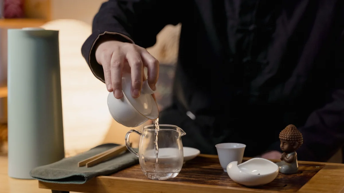 Pouring water into a glass teapot A person pouring water into a glass teapot