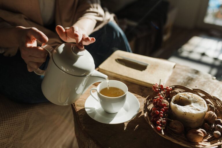 Tea being poured into a cup beside a teapot