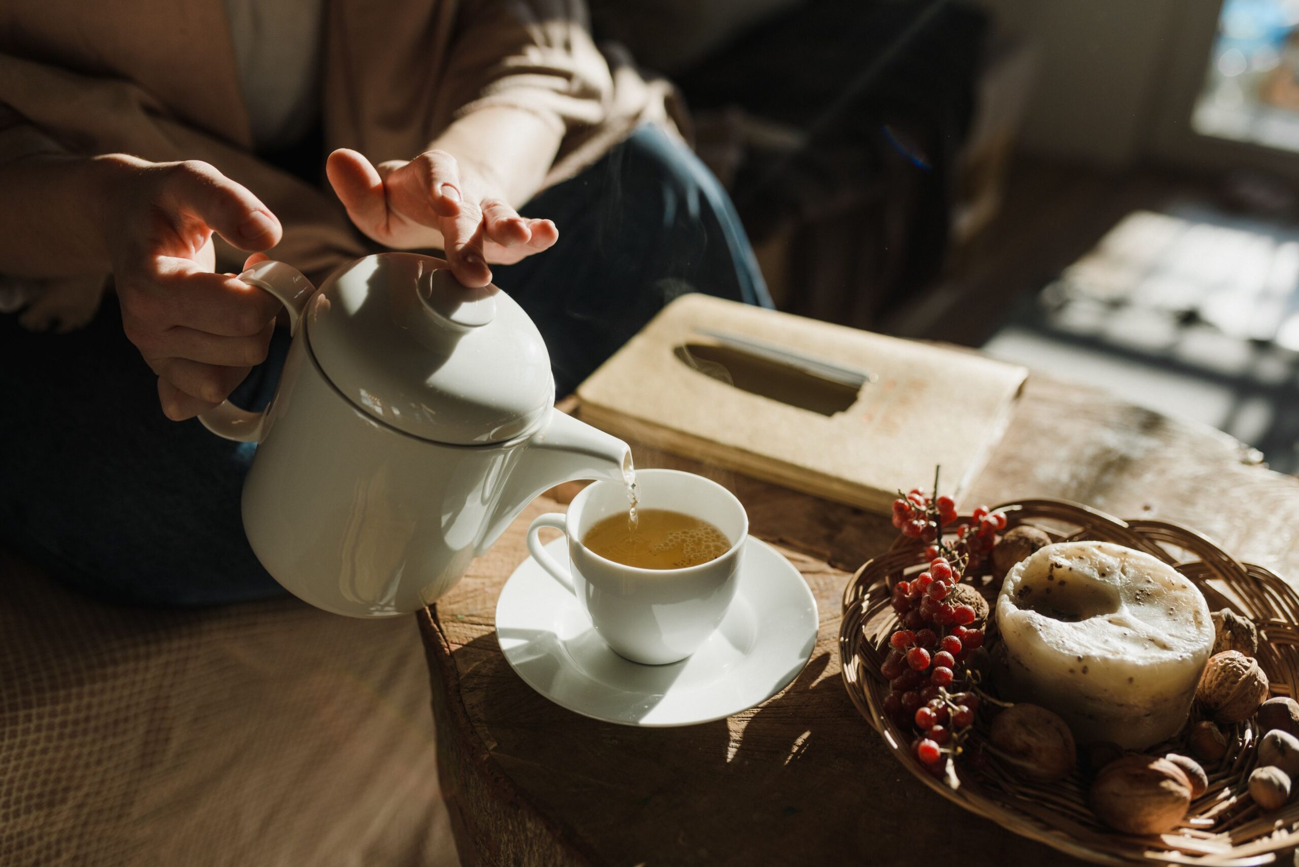Tea poured into a cup beside a teapot Tea being poured into a cup beside a teapot