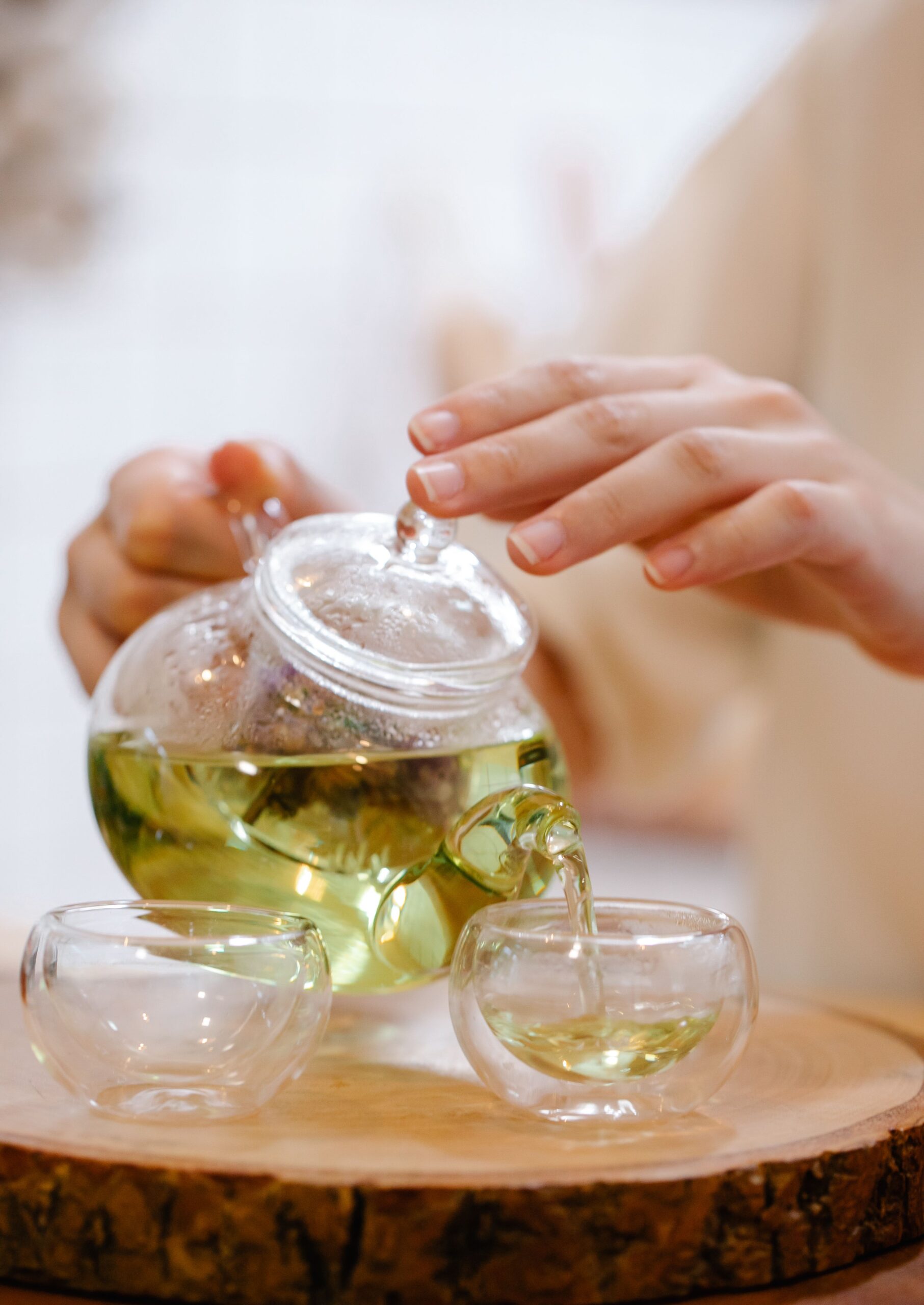 Glass teapot pouring tea into cups A glass teapot pouring tea into clear cups